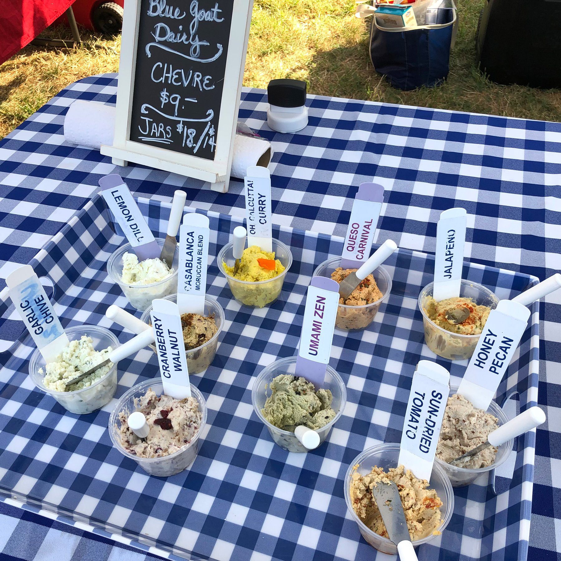 Sample cups of Blue Goat Dairy chevre on the market table, each labelled with its flavour